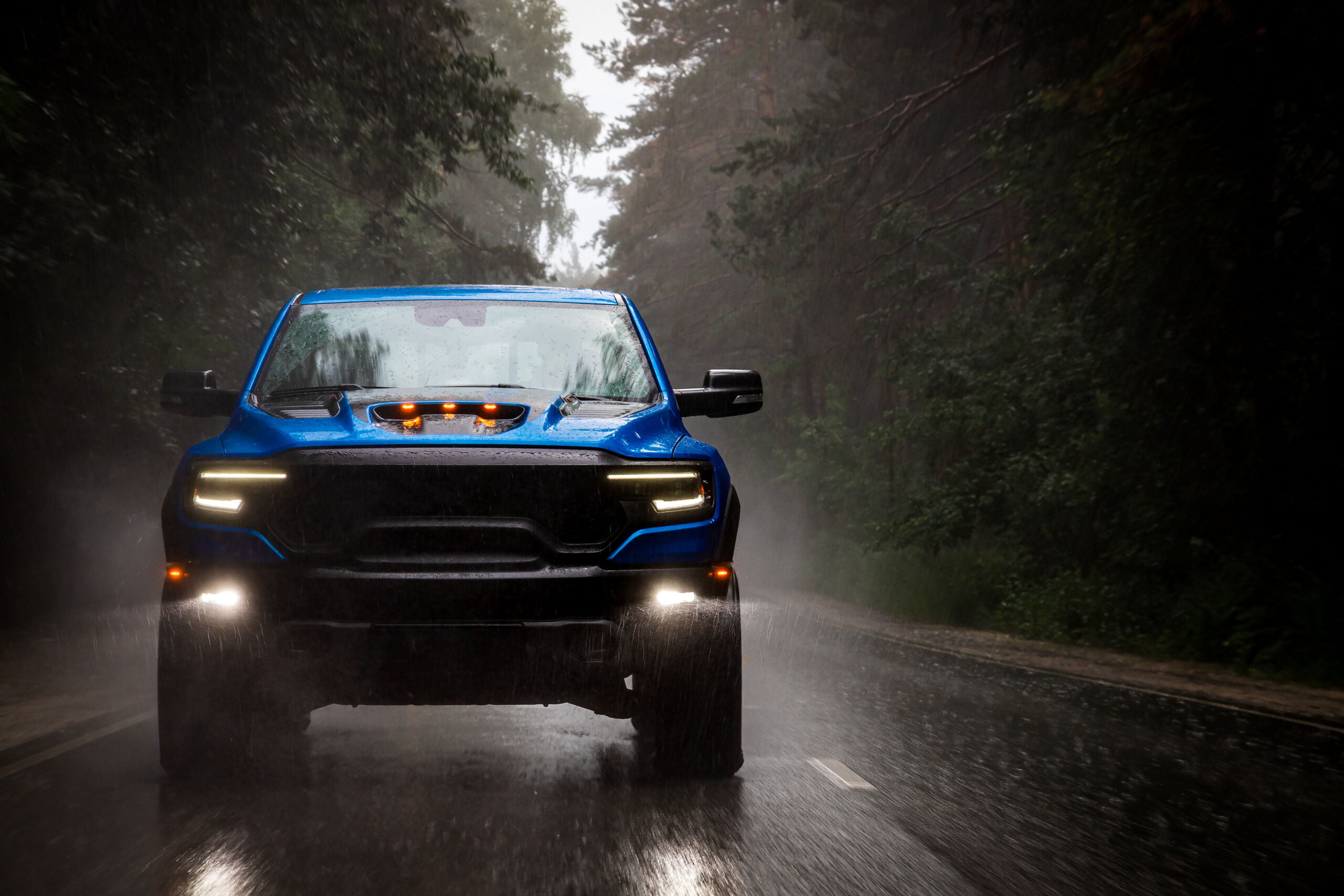 A blue new pickup truck is driving along a highway in the forest with a blurred background. Rust proofing